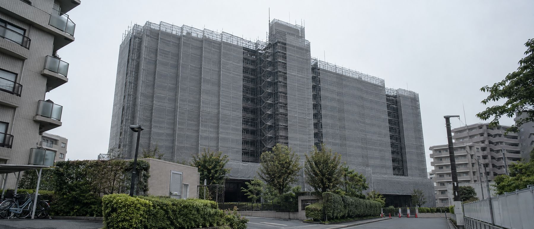 大規模修繕中の分譲マンション。足場と養生シートに覆われた外観